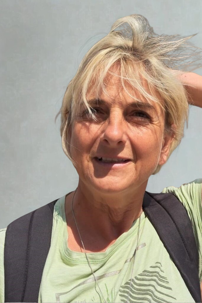 Frau mit blonden Haaren, die ein grünes T-Shirt trägt und in die Kamera lächelt.