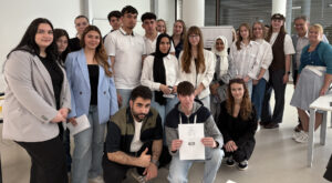 Eine Gruppe von 20 Personen posiert für ein Foto bei einer Präsentation in einem modernen Raum.