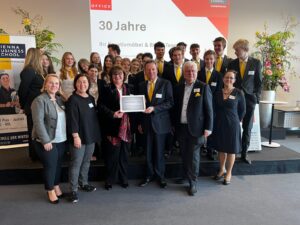 Gruppe von Menschen bei einem Jubiläumsevent in einem Konferenzraum