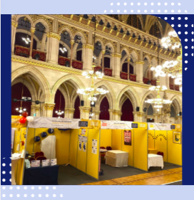 Gelbe Messestände in einer Halle mit hohen Decken und Kronleuchtern.